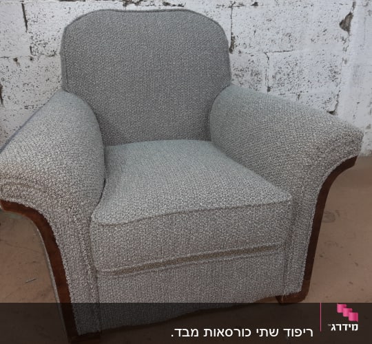 כורסה מרופדת בבד אפור עם מסגרת עץ